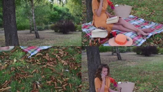 一个年轻的女人在外面野餐，看书，打电话，微笑，享受她的自由时间在一个美好的夏天。高清在线视频素材下载