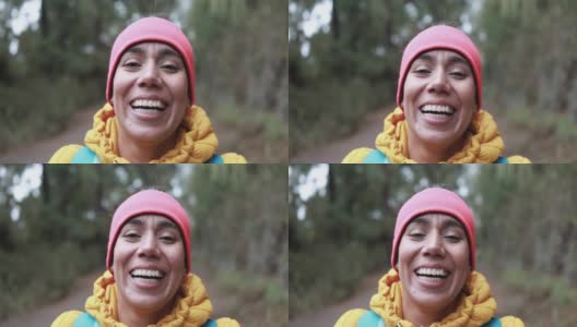 一位年轻的拉丁女子在森林里徒步行走时，对着镜头微笑高清在线视频素材下载