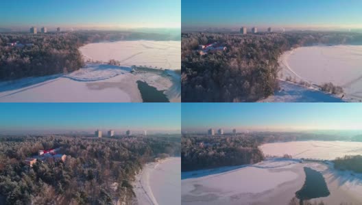 从空中俯瞰日落时冰冻的河流和森林的城市全景。高清在线视频素材下载