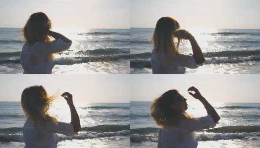 侧面美丽的女孩在比基尼和衬衫走在海岸和触摸她的金发。年轻女子在海滩上享受暑假。海边的背景。关闭侧视图慢动作高清在线视频素材下载