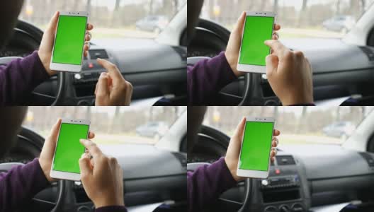 一只手拿着一个绿色空白屏幕的智能手机在车里为方向，按摩，位置，业务。男人坐在现代汽车里，用智能手机工作——绿色屏幕——特写。色度键。高清在线视频素材下载