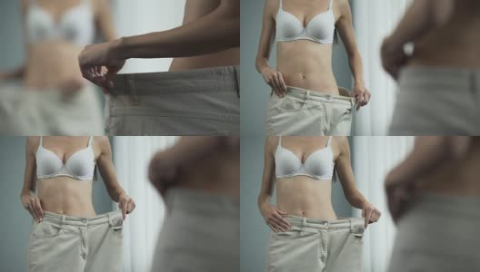 苗条的女人穿着大裤子在镜子前摆姿势，节食，减肥高清在线视频素材下载