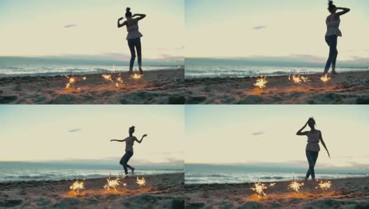 少女拿着烟花在沙滩上跳舞。慢动作拍摄高清在线视频素材下载