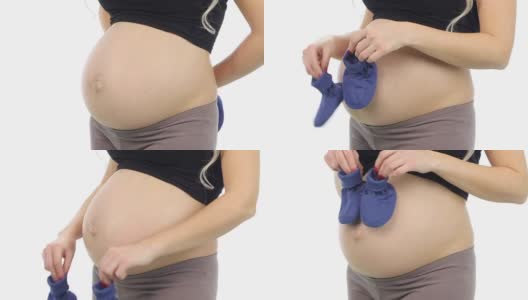 一名孕妇将蓝色的婴儿靴子举到她的腹部，等待着白色的婴儿，特写高清在线视频素材下载