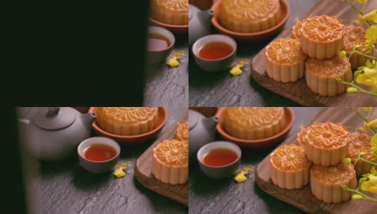 美丽的月饼在木托盘与茶和花在黑石板背景。中国传统的中秋节观念。高清在线视频素材下载