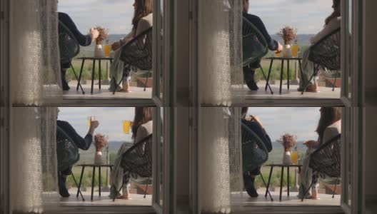 一对夫妇坐在阳台上，一边聊天一边喝果汁高清在线视频素材下载