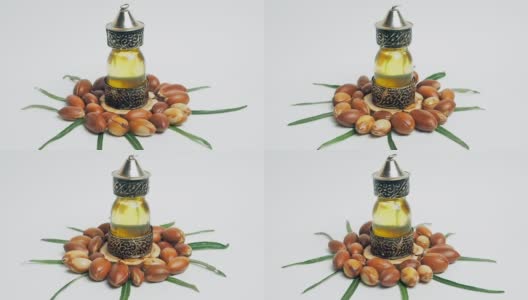 东方玻璃和金属瓶里的摩洛哥坚果油和白色背景上绿色叶子的摩洛哥坚果高清在线视频素材下载
