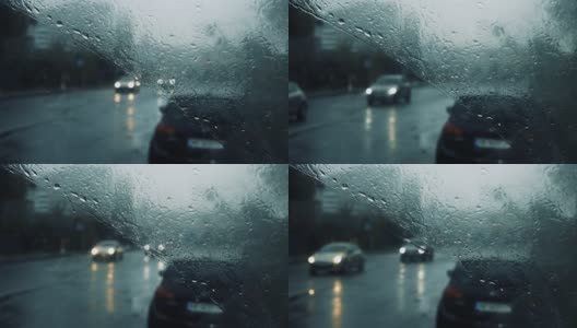 雨点落在汽车的挡风玻璃上，雨点顺着玻璃流下，汽车在道路上运动高清在线视频素材下载