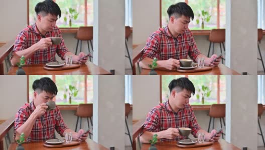 4K年轻的亚洲男子用智能手机查看电子邮件，喝咖啡高清在线视频素材下载