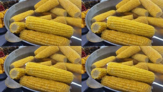 在夏季露天街头市场，用开水在平底锅中准备金黄色天然成熟的玉米芯。高清在线视频素材下载