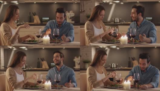 一对美丽的夫妇在厨房里吃烛光晚餐。他们吃喝聊天。两个都有好心情和微笑很多。结束运动。高清在线视频素材下载