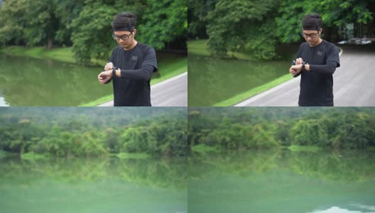 亚洲男子开始慢跑使用他的心率运动手表在自然公园高清在线视频素材下载