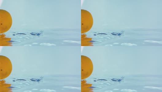 一个橙子落在闪亮的水面上的慢动作镜头高清在线视频素材下载