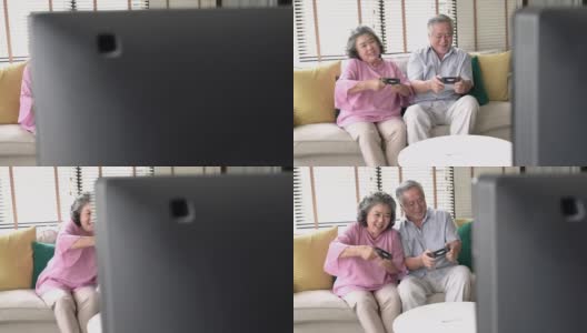 亚洲成熟的老年人在家里的客厅玩电子游戏快乐和激动的情绪。用操纵杆控制游戏。家庭、科技、娱乐、放松的理念。高清在线视频素材下载