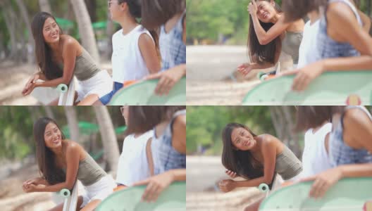 一群快乐的亚洲女性朋友在玩完滑板后坐在沙滩上聊天高清在线视频素材下载