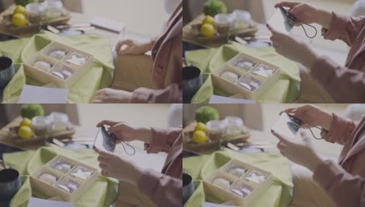 亚洲中国女子在客厅用智能手机拍摄朋友送的月饼礼盒高清在线视频素材下载