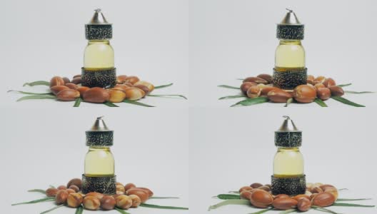 东方玻璃和金属瓶里的摩洛哥坚果油和白色背景上绿色叶子的摩洛哥坚果高清在线视频素材下载