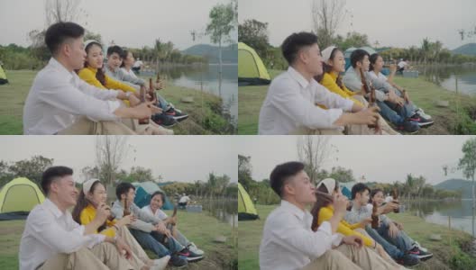 群亚洲四青年朋友男女在河边野餐野营，他们有说有笑，喝着庆祝欢呼啤酒。高清在线视频素材下载