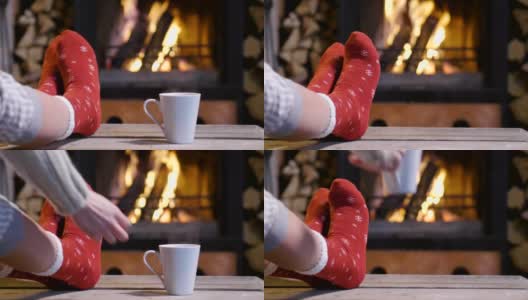 寒冷的秋天或冬天的夜晚。人们拿着毯子和茶在火炉旁休息。脚在羊毛袜子的特写照片。舒适的场景。高清在线视频素材下载