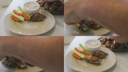 “白种人之手”将烤鸡翅放在盘子上，旁边是胡萝卜和芹菜根，还有一小碗牧场蘸酱高清在线视频素材下载