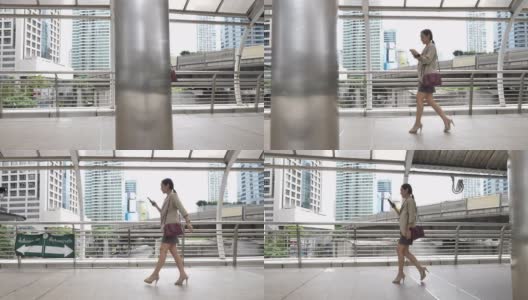 女商人使用智能手机在城市中步行上班，早上通勤上班高清在线视频素材下载