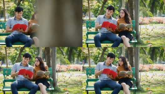 两个亚洲年轻的大学生或情侣正在户外公园的长椅上看书高清在线视频素材下载