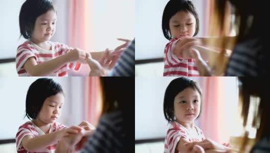 年轻的母亲在孩子的手上涂防晒霜高清在线视频素材下载