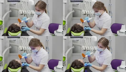 年轻女牙医戴面罩和手套，使用牙科紫外线光设备进行聚合物硬化高清在线视频素材下载