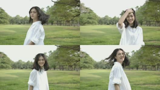 一个年轻迷人的亚洲女人的特写在一个夏天的日落公园散步，她走回去看镜头。一个快乐的黑色长发女孩的肖像在公园日落。缓慢的运动。高清在线视频素材下载