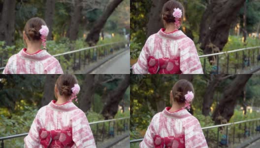 快乐年轻美丽的亚洲女人女孩穿着粉红色的传统日本和服走在公园的街道上，看着远离东京城市，日本的4K后视图高清在线视频素材下载