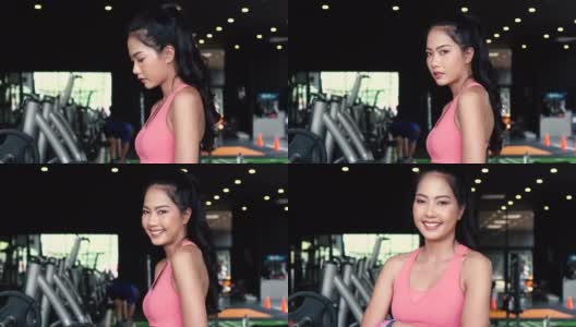 微笑和坚定的年轻亚洲女运动员看着镜头，双臂交叉，站在健身房健身中心高清在线视频素材下载