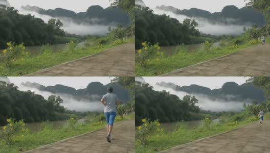 健康的生活方式。一个穿着运动服的女人，在雾气弥漫的山谷中跑步锻炼，周围是绿色的植被。高清在线视频素材下载