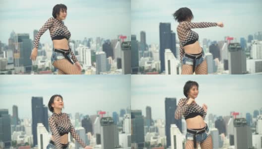 年轻的亚洲女子舞者练习在城市景观背景的屋顶上跳舞。在摩天大楼上跳舞的艺人表演韩国流行女团高清在线视频素材下载