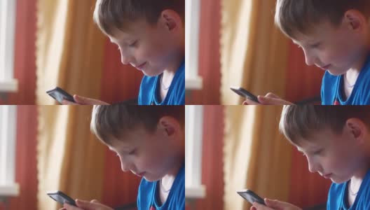 一名7 ~ 9岁的白人少年正在家中用智能手机上网。一个拿着手机的孩子的头像。网上的日常生活。有选择性的重点高清在线视频素材下载