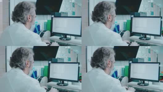 一位上了年纪的医生在一个白色的实验室里用电脑处理文档高清在线视频素材下载