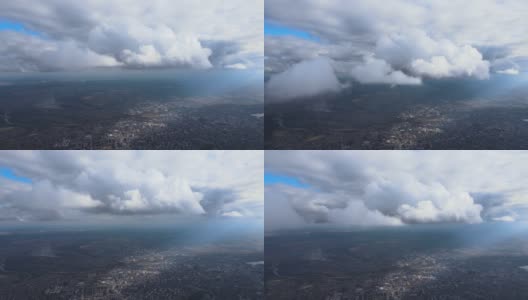 从高空的飞机窗口鸟瞰，远处的城市被暴雨前形成的蓬松的积云所覆盖高清在线视频素材下载