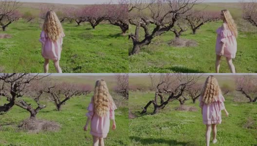 金发女人穿着粉红色的裙子走过一个盛开的花园和树木高清在线视频素材下载