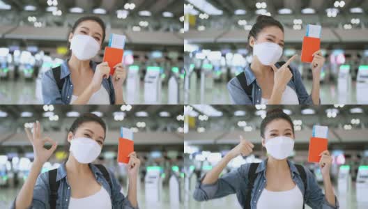 快乐微笑的亚洲成年女性戴着口罩，手势显示护照和空白屏幕的智能手机在机场候机楼，亚洲女性在机场站封锁后准备出行高清在线视频素材下载