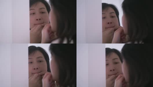 一名泰国妇女正在镜子旁挤她脸上和嘴上的痘痘高清在线视频素材下载