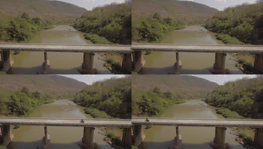 航拍冒险摩托车骑在横跨泰国南省南河的一座桥上俯视图高清在线视频素材下载