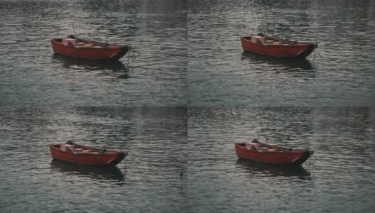 一艘红色的小渔船在平静的水面上抛锚高清在线视频素材下载