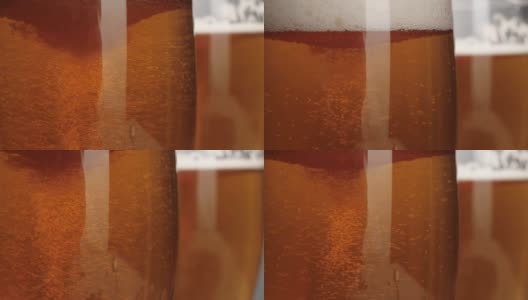 新鲜的啤酒。一杯清凉可口的啤酒放在一张木桌上，背景是开心果。冰凉的新鲜啤酒，带有水滴，泡沫和泡沫。微距镜头。4 k高清在线视频素材下载