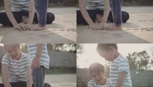 年轻的母亲和小男孩在沙滩上玩沙子高清在线视频素材下载