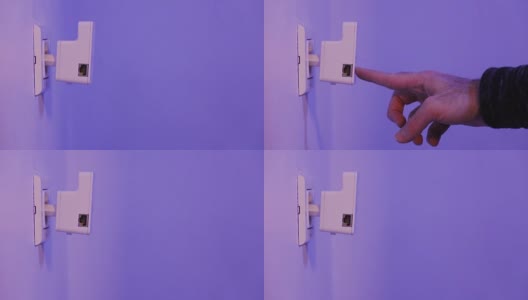 男子将手指按在WiFi中继器的WPS按钮上，该按钮位于墙上的电源插座上高清在线视频素材下载