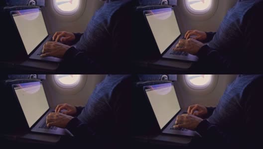 一名男子在飞机上敲打笔记本电脑——近距离观察高清在线视频素材下载