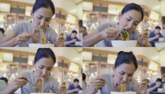 年轻的亚洲女人饿着吃炒面猪肉和甘蓝浸在肉汁(Radna)著名的泰国食物，吃看起来很好吃。高清在线视频素材下载