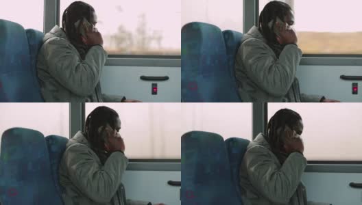一名戴着面具的黑人在公交车窗口边打电话，把电话放在耳边高清在线视频素材下载