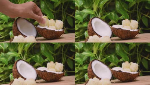 特写镜头:手从椰子壳里摘出甜椰子球，然后把吃了一半的椰子放回去。传统印度甜品也被称为Kopra pak。高清在线视频素材下载