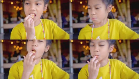 一个亚洲小女孩正在咖啡馆吃饼干(特写)。slowmotion。高清在线视频素材下载