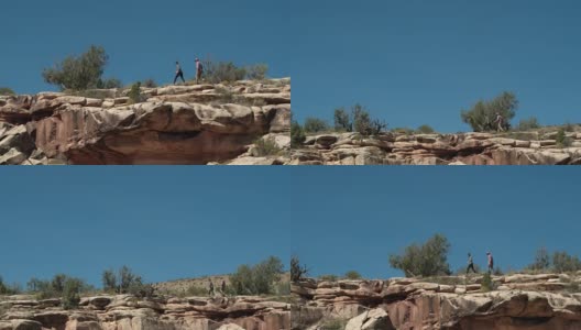 从下方航拍的两个人走在科罗拉多州大Junction沙漠的科罗拉多国家纪念碑的岩石边缘上高清在线视频素材下载